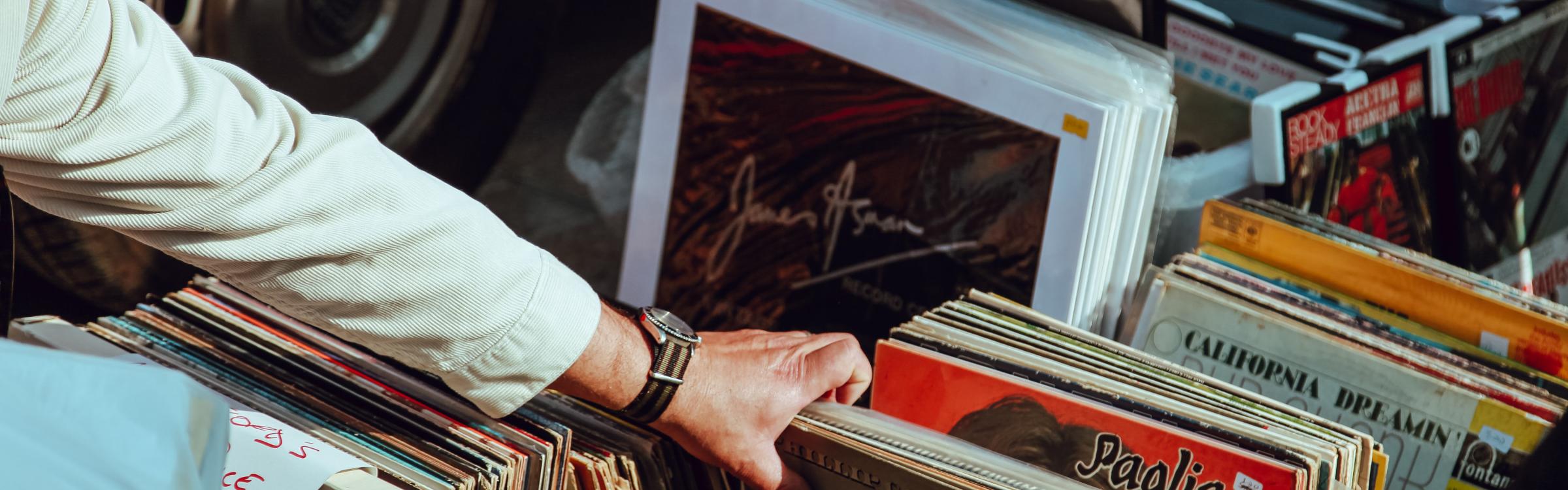 Persoon kijkt tussen assortiment vinyl platen op een rommelmarkt