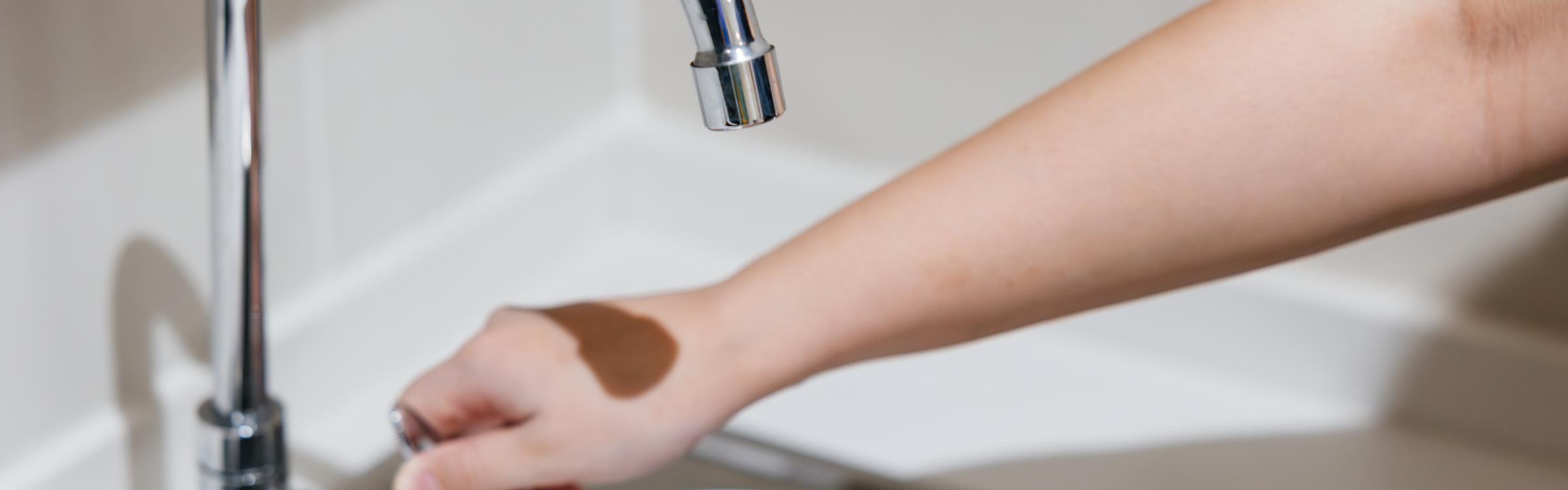 Persoon houdt hand onder kraan maar er komt geen water uit