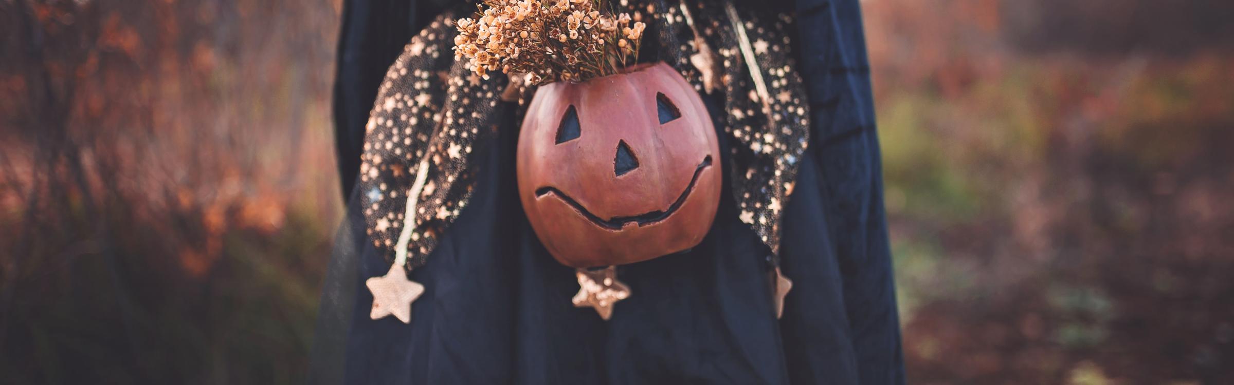 Meisje verkleed voor Halloween met een pompoenlantaarn in de hand