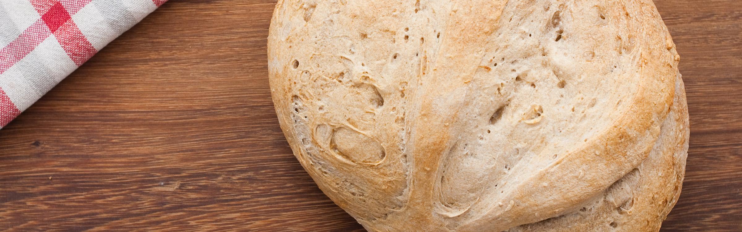 Vers gebakken brood op houten tafel met geruite handdoek