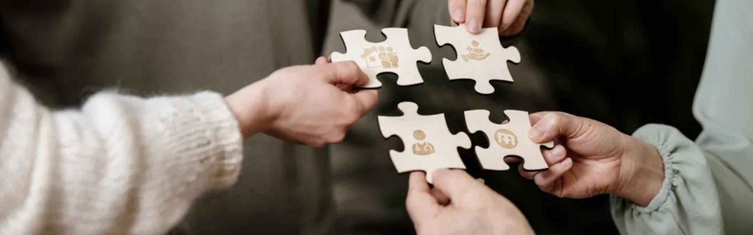 4 mensen houden 4 puzzelstukje vast met icoontjes op die met gezondheidszorg te maken hebben