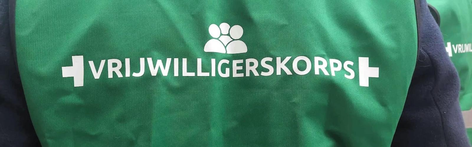 Persoon heeft een groen hesje aan van het vrijwilligerskorps